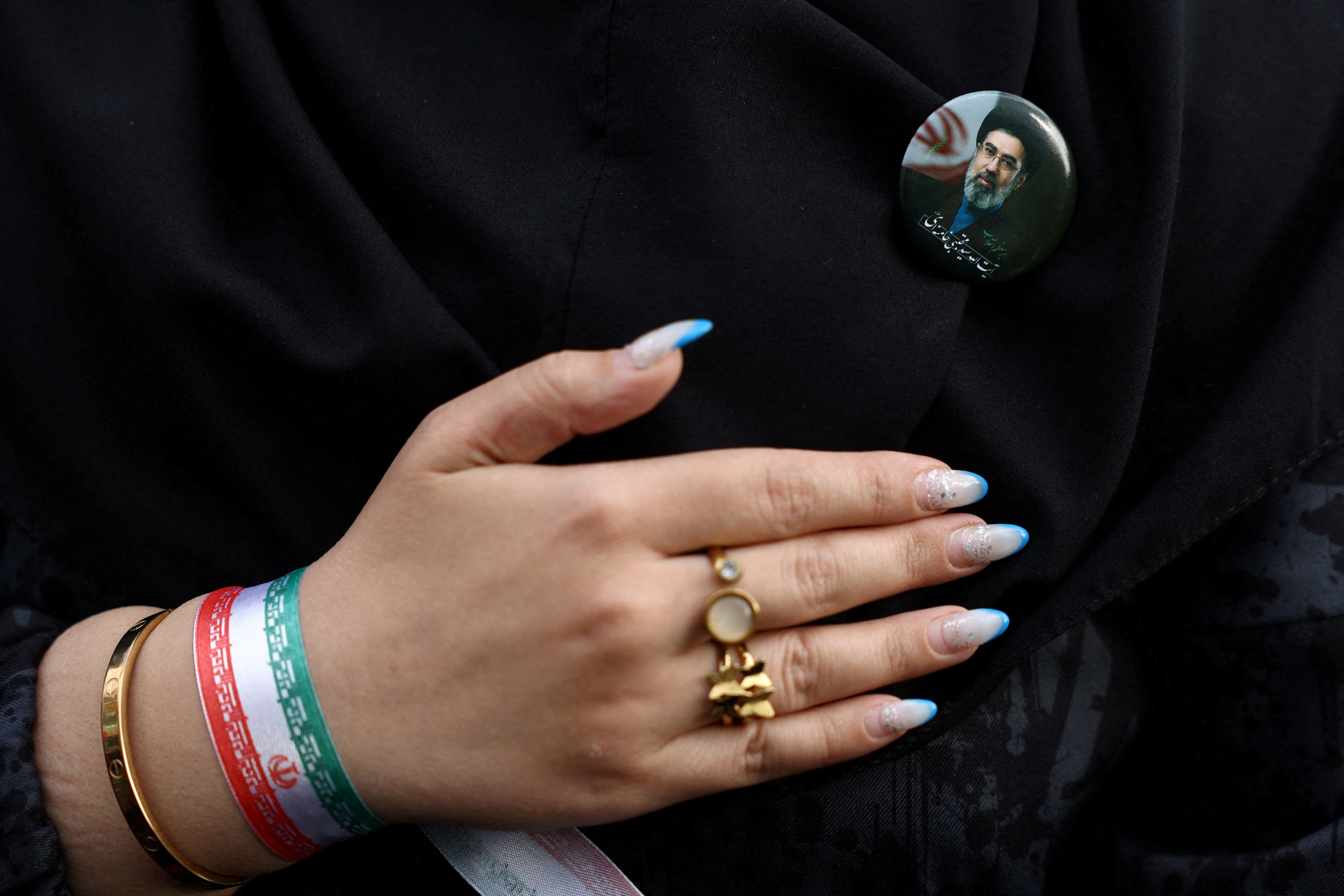 A woman wears a badge with a picture of Iran’s new Supreme Leader, Mojtaba Khamenei, during a rally in Tehran, Iran, April 29, 2026. 