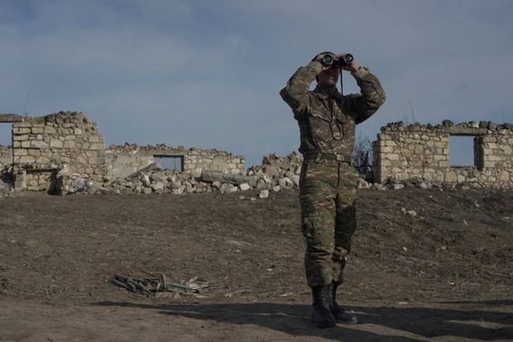 An ethnic Armenian soldier looks through binoculars as he stands at fighting positions near the village of Taghavard in the region of Nagorno-Karabakh, January 11, 2021.