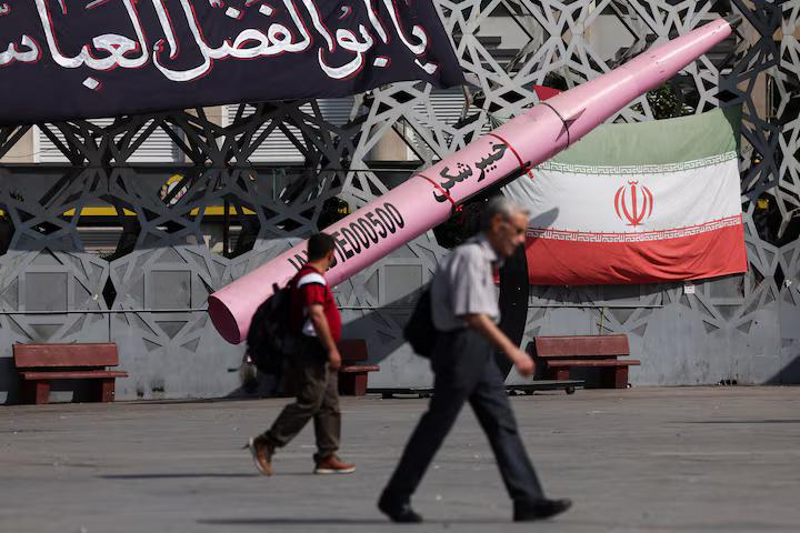 People walk past a mockup of an Iranian missile and an Iranian flag at Imam Hussein Square in Tehran on July 12, 2026. Majid Asgaripour/WANA via Reuters.