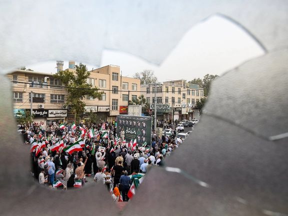 A rally in support of Iran's military operations against Israel seen through a broken window, Karaj, Iran, June 24, 2025