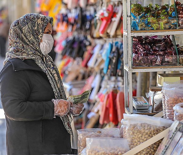 A woman shopping in Tehran with Iranian currency in hand