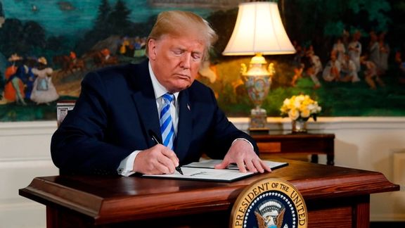 Former president Donald Trump signs a proclamation declaring his intention to withdraw from the JCPOA Iran nuclear agreement in the Diplomatic Room at the White House in Washington, May 8, 2018.