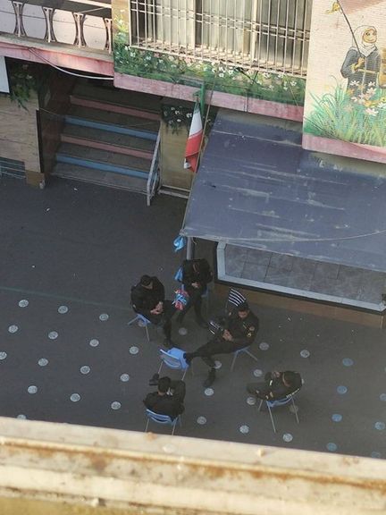 Uniformed officers sit in a school courtyard beneath an Iranian flag in an image shared on social media on March 3, 2026.