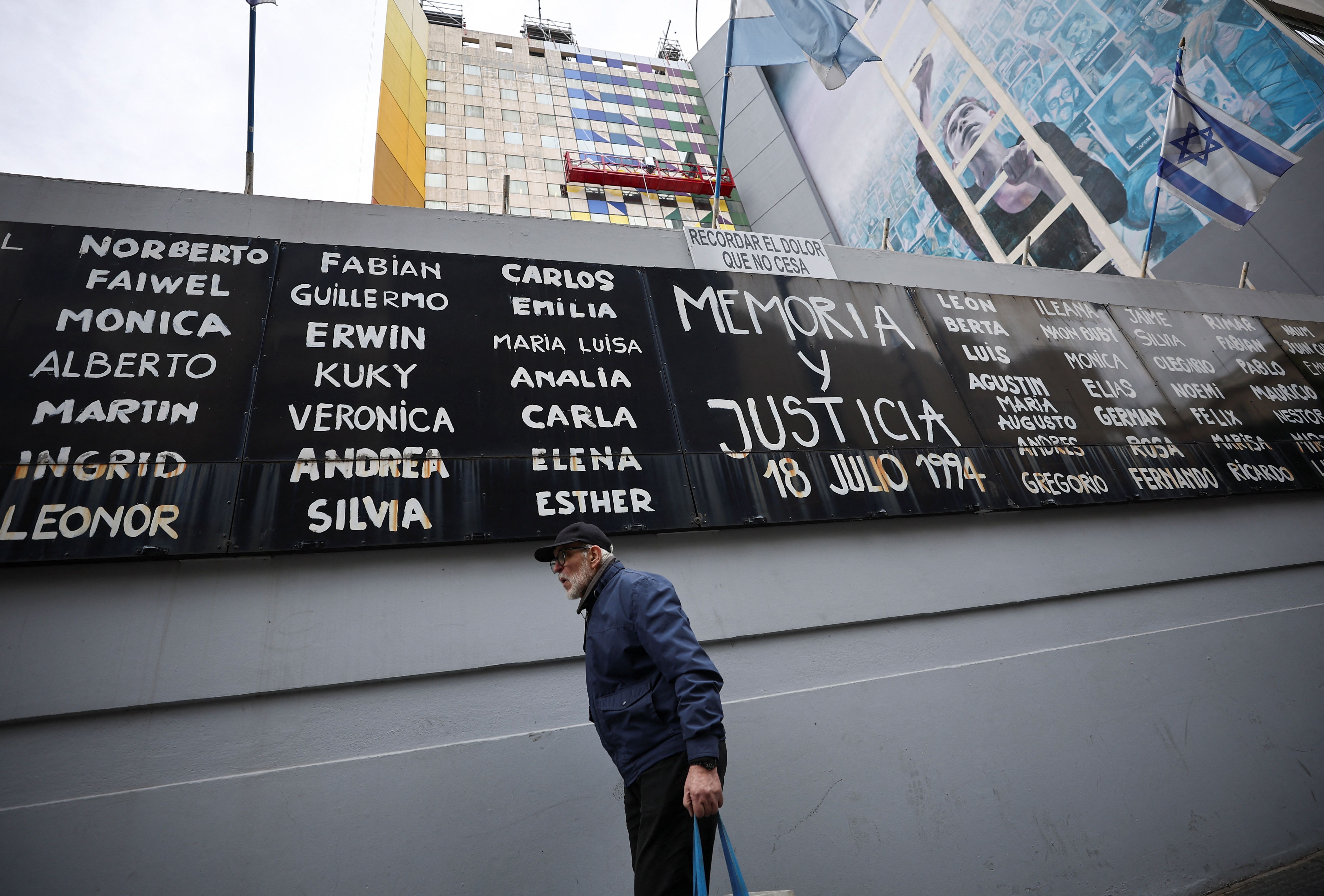 A man walks past a banner reading "Memory and justice" and the names of the victims of the 1994 bombing attack on the Argentine Israelite Mutual Association (AMIA) community centre a day after Argentina's highest criminal court blamed Iran for the attack, in Buenos Aires, Argentina April 12, 2024. 