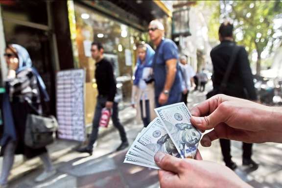 A man selling US dollars outside a currency exchange office in Tehran. Undated