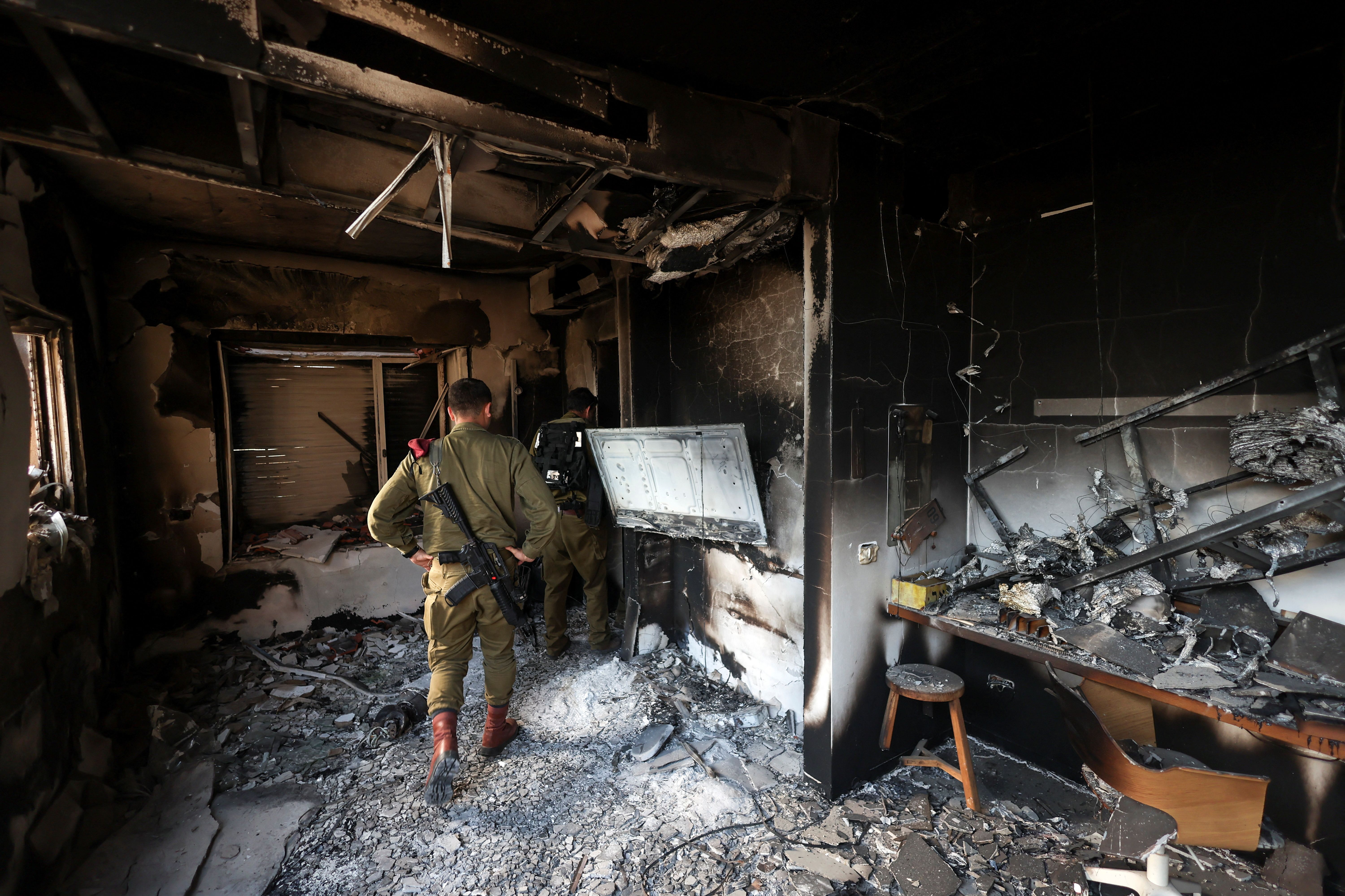 Israeli soldiers inspect the remains of a burnt house, following a deadly infiltration by Hamas gunmen from the Gaza Strip, in Kibbutz Beeri in southern Israel October 17, 2023. 
