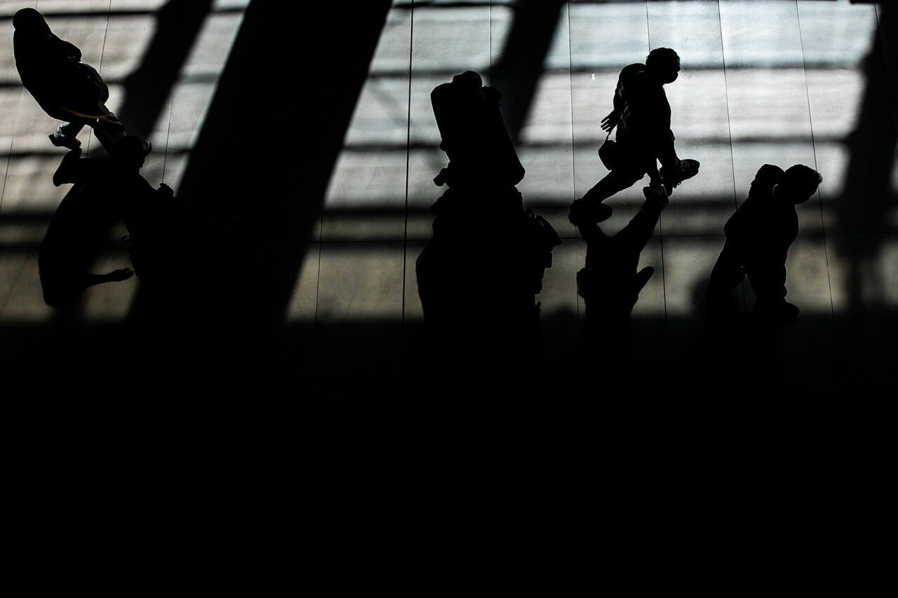 Visitors walk through a book fair in Tehran, their silhouettes cast across the exhibition hall floor, May 28, 2026