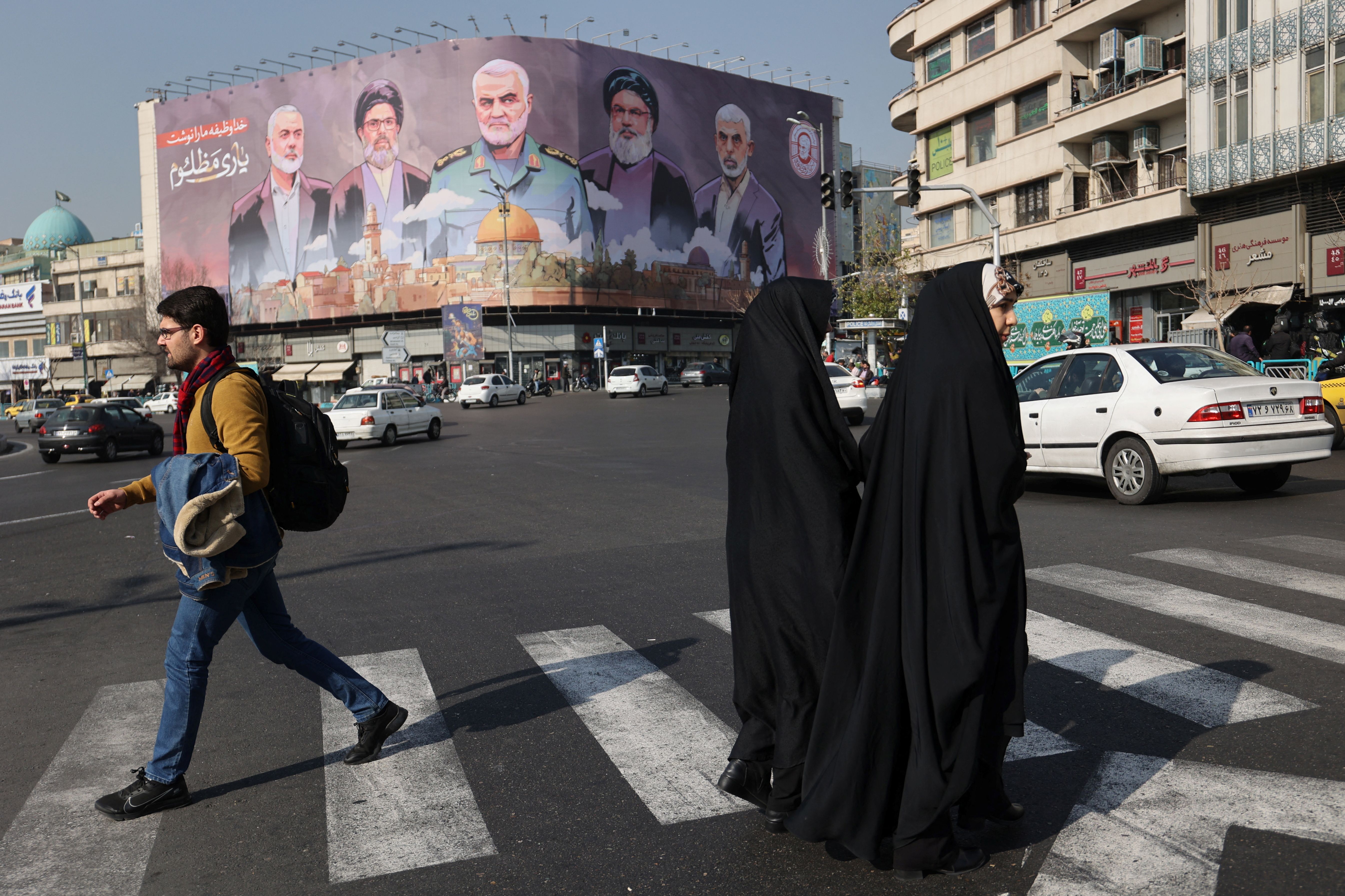 Iranians walk next to a billboard with a picture of late Hamas leader Ismail Haniyeh, late senior Iranian military commander General Qassem Soleimani, late Lebanon's Hezbollah leader Sayyed Hassan Nasrallah and late Hamas leader Yahya Al-Sinwar on a street in Tehran, Iran, January 16, 2025.