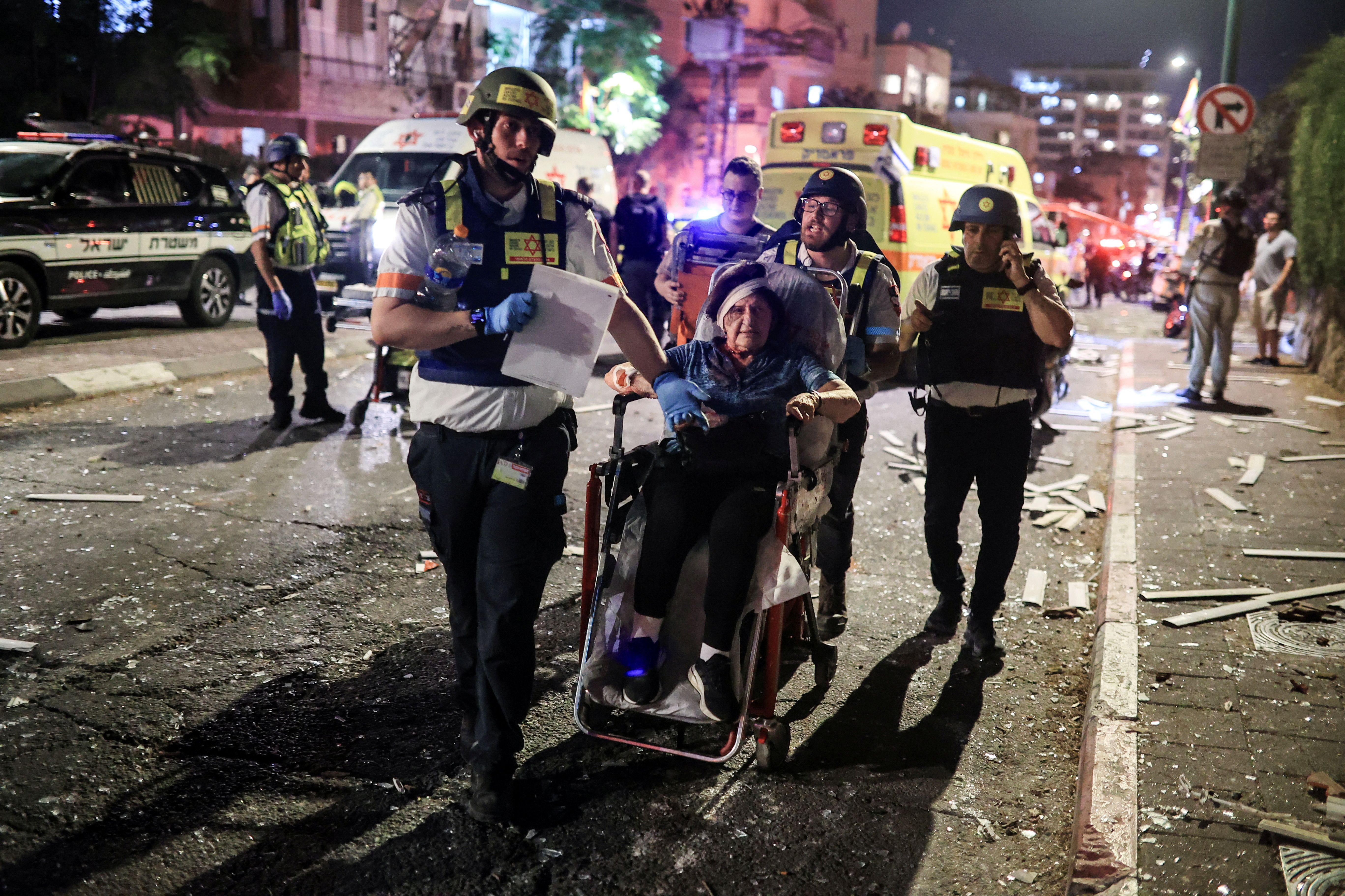 Rescue personnel evacuate a wounded woman at an impact site following missile attack from Iran on Israel, in Ramat Gan, Israel June 13, 2025 