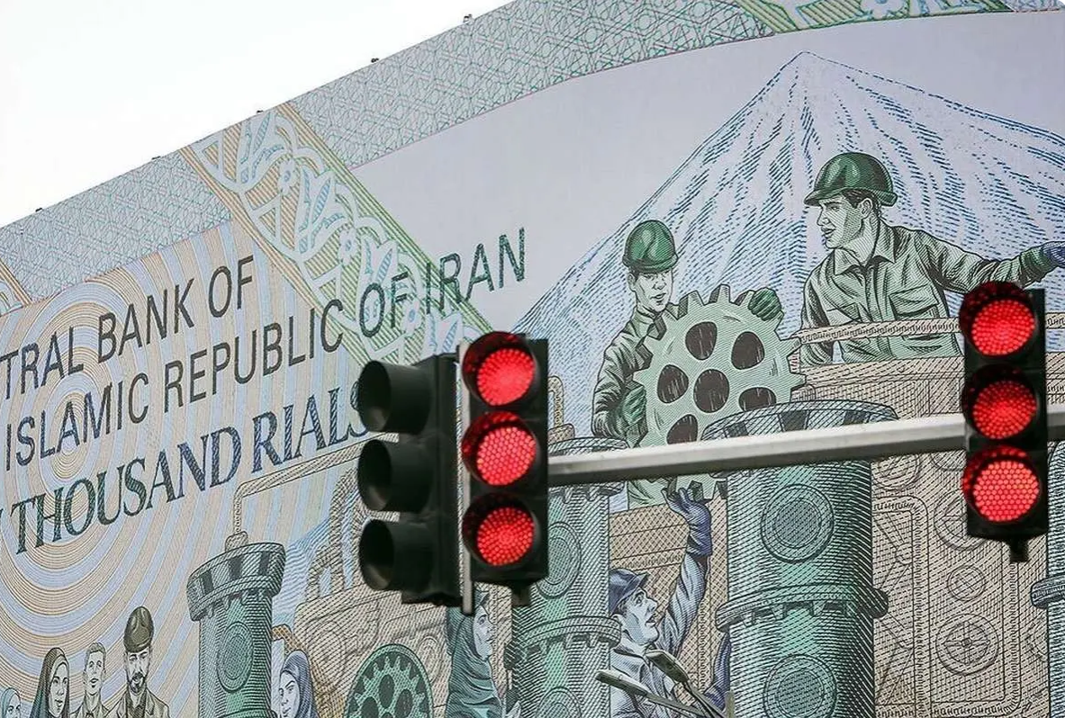 File photo of a billboard featuring Iran's 10,000-rial banknote is seen behind red traffic lights in Tehran, Iran.