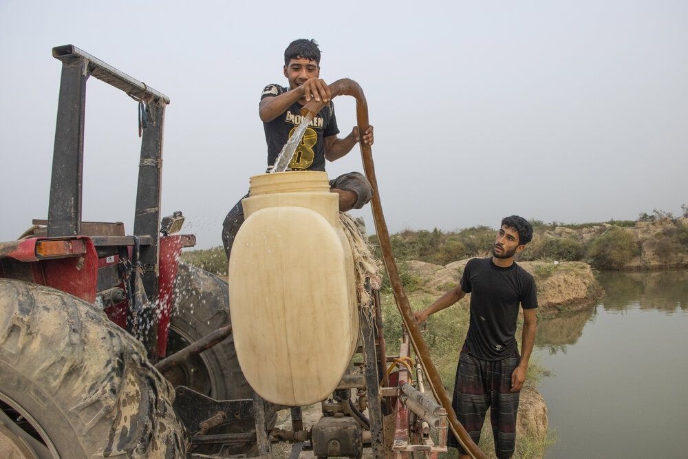 Young men pumping water from a pond near the southern town of Karkheh, Iran, July 23, 2025