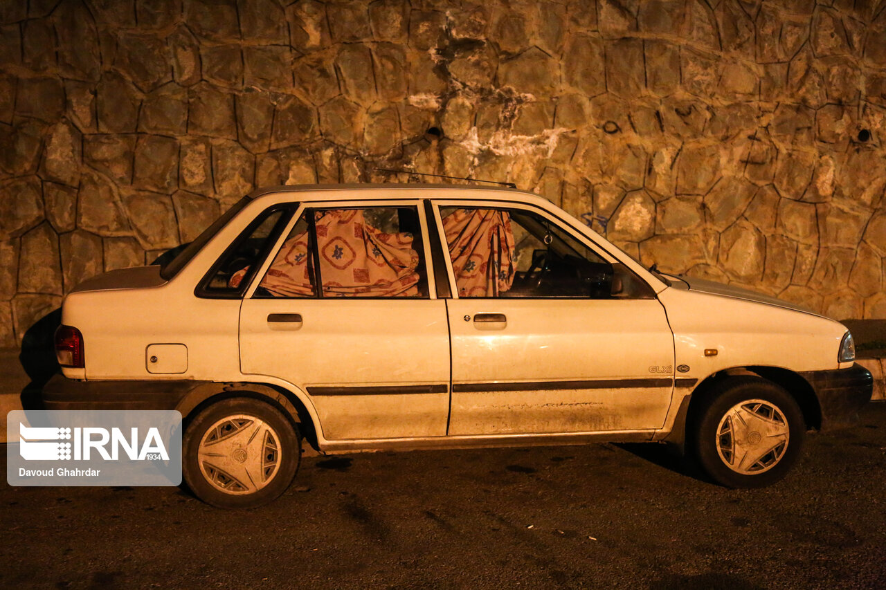 A photo of a car parked in northern Tehran, its driver asleep inside.
