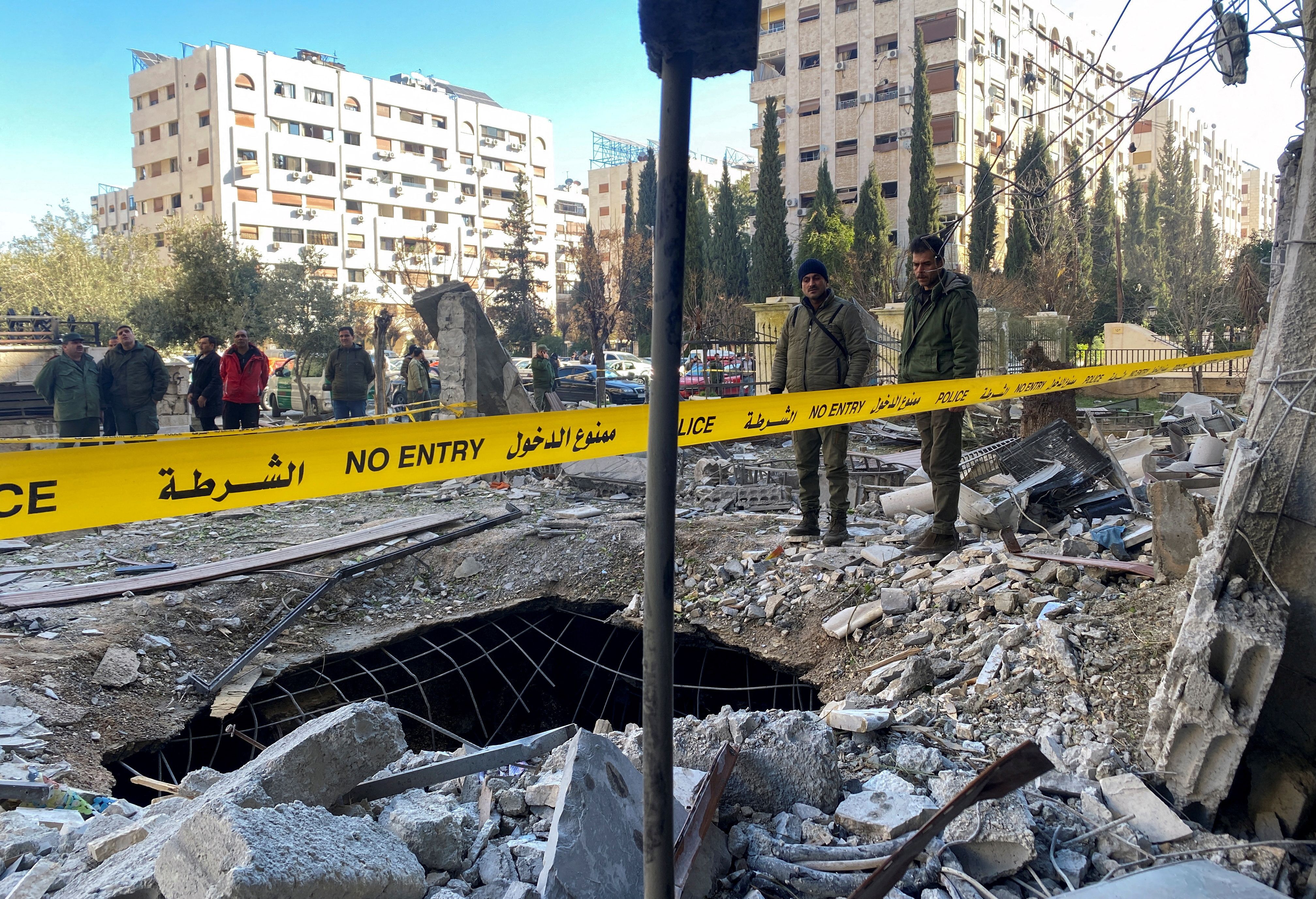 Police officers stand amid the rubble of a damaged building at the site of a rocket attack in the Kafr Sousa neighbourhood of central Damascus, Syria, February 19, 2023. 