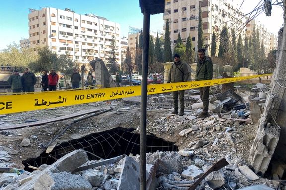 Police officers stand amid the rubble of a damaged building at the site of a rocket attack in the Kafr Sousa neighbourhood of central Damascus, Syria, February 19, 2023.